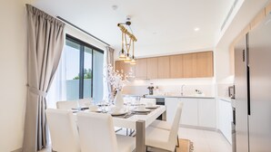 A modern kitchen with a built-in island, white cabinetry, and stainless steel appliances.