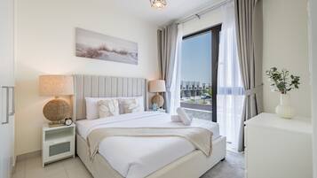 A modern hotel room with a large bed, bedside lamps, a view of the city, and a plant on the desk.