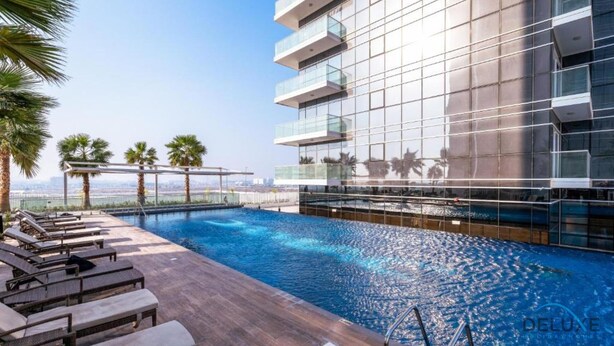 Un hotel moderno con piscina en la azotea, sillones de descanso y vistas despejadas del horizonte urbano.