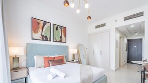 Una habitación de hotel moderna con una cama grande, mesitas de noche, un escritorio y un comedor.