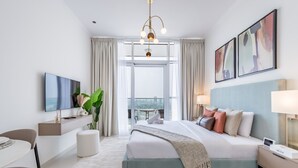 Una habitación de hotel moderna con una cama grande, un televisor de pantalla plana, un escritorio y vistas de la ciudad a través de amplias ventanas.