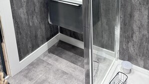 A modern bathroom with a glass shower enclosure, a white sink, and a dark floor. - Modern City Apartment in Manchester (Manchester)