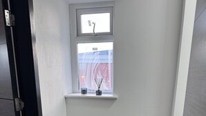 A narrow hallway with a small window, a glass jar, and a power outlet on the wall. - Modern City Apartment in Manchester (Manchester)
