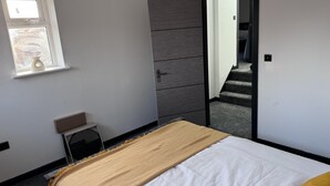 A bedroom with a bed, a wardrobe, a small table, and a window. - Modern City Apartment in Manchester (Manchester)
