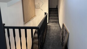 Una escalera con barandilla de madera y peldaños alfombrados que conduce a un piso superior.