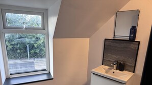 Un baño con ventana, lavamanos y espejo.