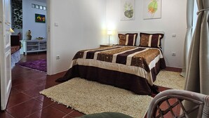 Een slaapkamer met een bed, nachtkastje, lamp en raam met gordijnen.