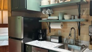 A kitchen with green cabinets, a stainless steel refrigerator, a coffee maker, and a sink. - Romantic Hot Tub Get-a-way! (Coleraine)