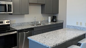 A modern kitchen with granite countertops, stainless steel appliances, and a bar stool. - Downtown Adrian apartment with parking and wifi (Adrian)