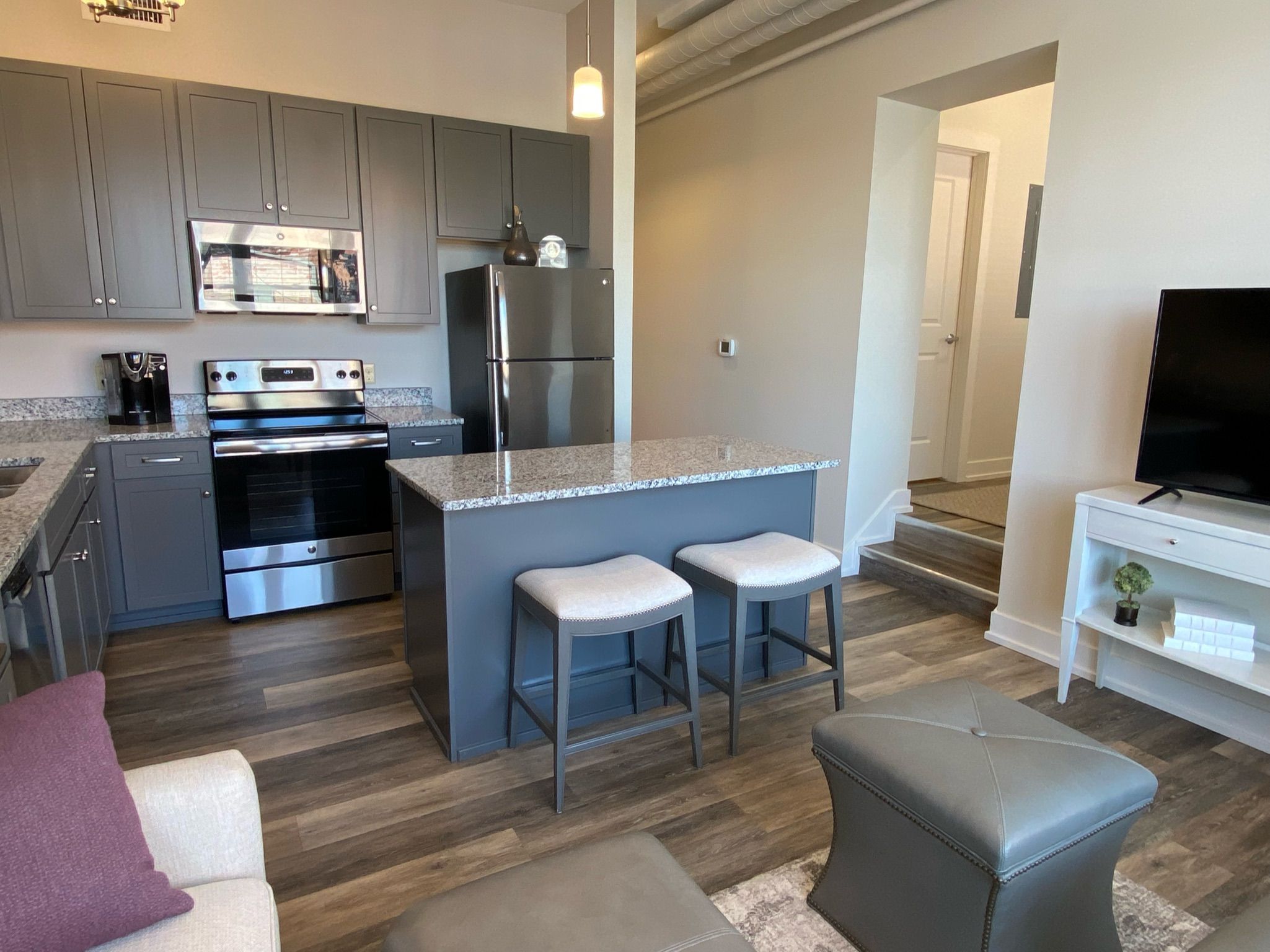 A modern kitchen with stainless steel appliances, a granite countertop, and a bar area with stools.