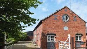 A red brick building with a circular window and a sign indicating it is a 'FORCE VILL FARM'. - Forge Masters Cottage (Middlewich)