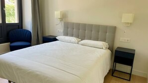 A hotel room with a large bed, two bedside tables, a chair, and a window with curtains. - Sueño Indiano, Bajo Norte (Muros de Nalón)