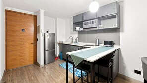 A compact kitchen with a refrigerator, microwave, and toaster. -  Oceana Suites Briones Luco (Santiago)
