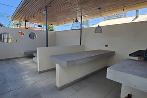 An outdoor patio area with a concrete bench and a table, surrounded by walls with circular cutouts and a wooden ceiling. -  Oceana Suites Briones Luco (Santiago)