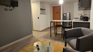 Una cuina moderna amb zona de menjador, nevera i televisió plana penjada a la paret.