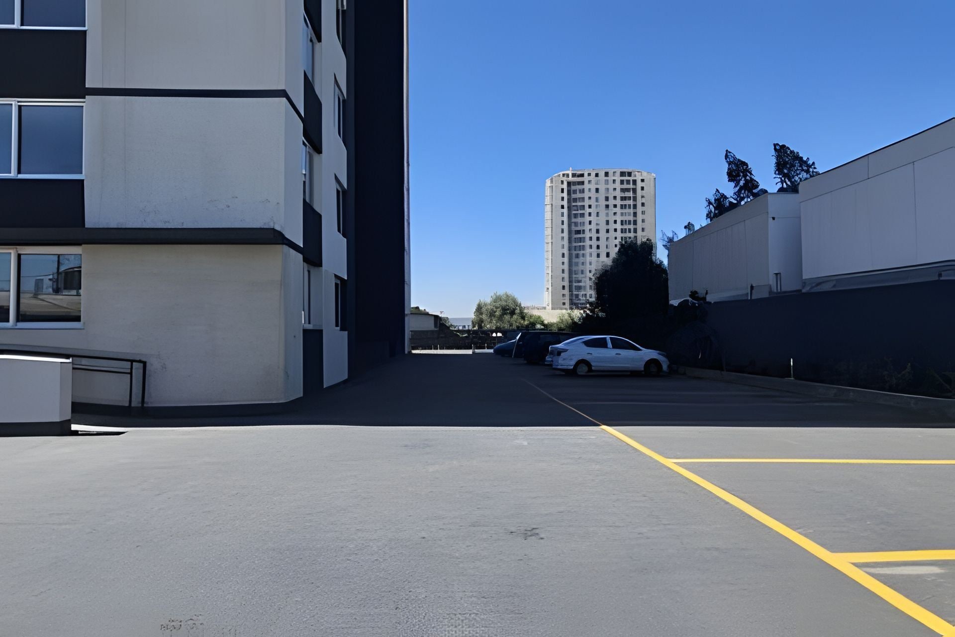 A parking lot with a white car parked near the building.