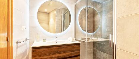 Une salle de bain moderne avec un meuble-lavabo en bois, deux miroirs ronds et une douche à parois de verre.
