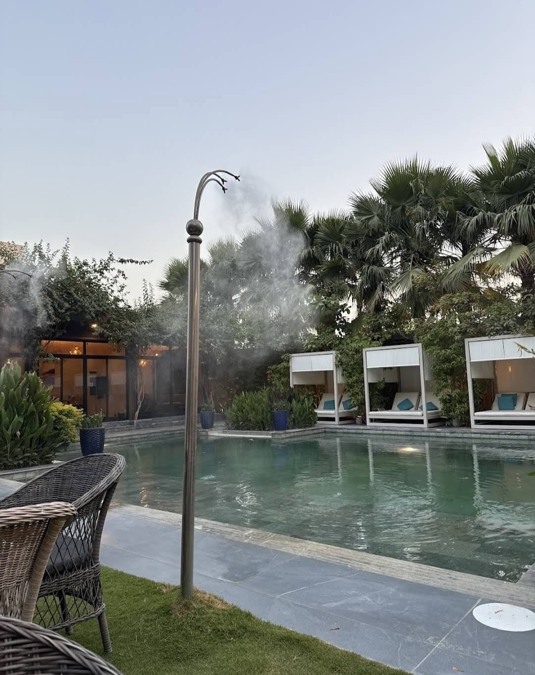 Un área de piscina con fuente, sillas de descanso y un edificio de diseño moderno.