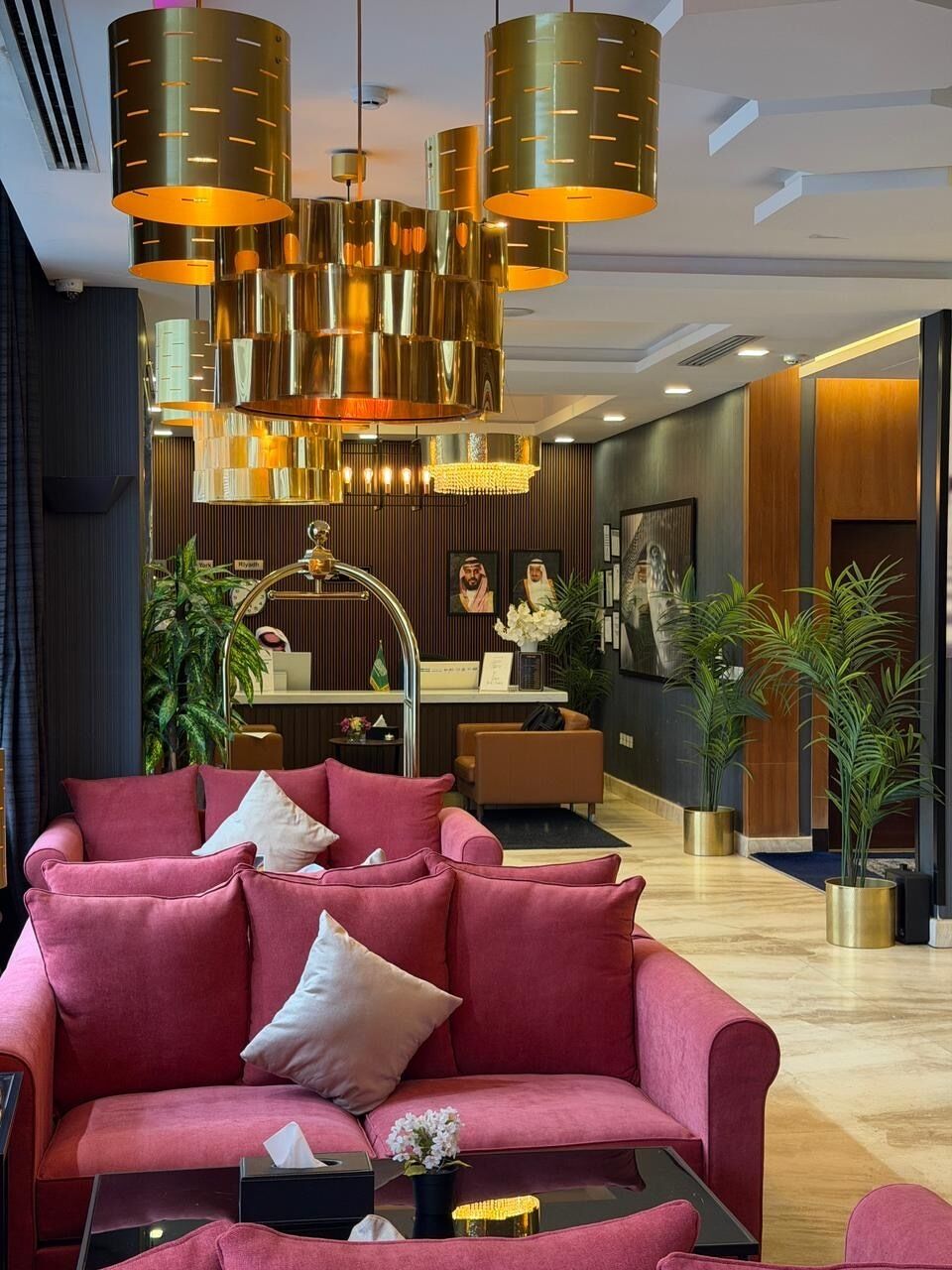 Un moderno vestíbulo de hotel con un sofá rojo, una recepción y una araña.
