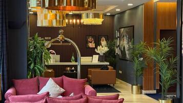A modern hotel lobby with a red sofa, a reception desk, and a chandelier.