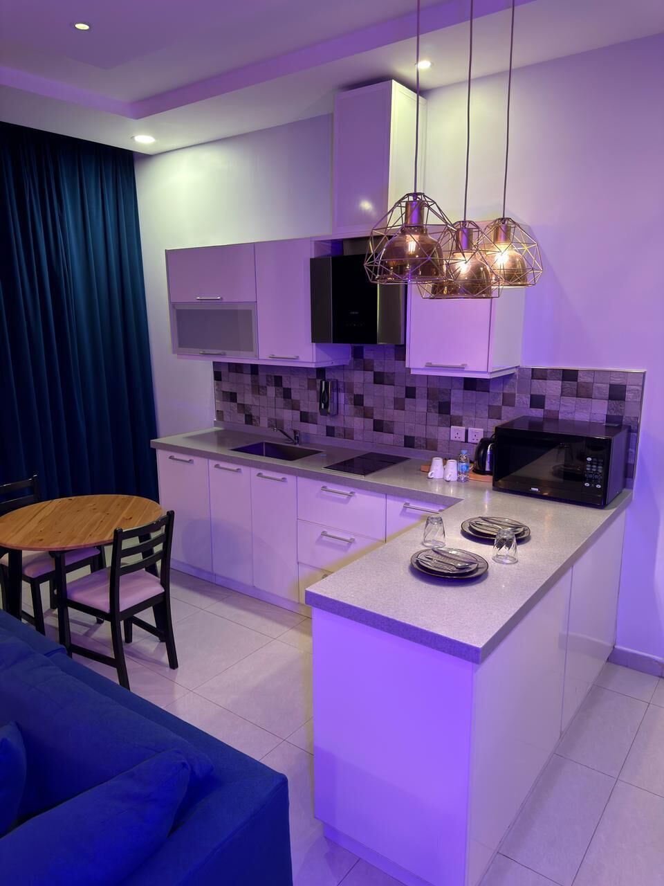 A modern kitchen with a central island, built-in appliances, and pendant lighting.