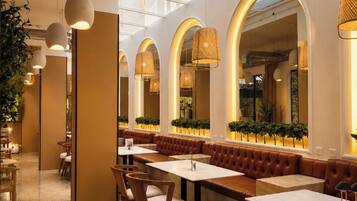 A modern restaurant interior with high ceilings, arched windows, and pendant lighting.