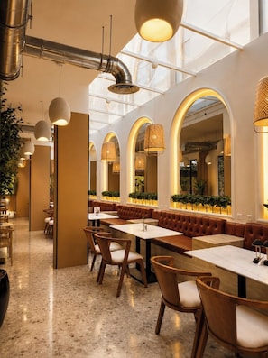 A modern restaurant interior with high ceilings, arched windows, and pendant lighting. - Dana Serviced Apartments2 (Riyadh)