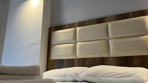 Ein Hotelzimmer mit Bett, Kopfteil und Wandleuchte.