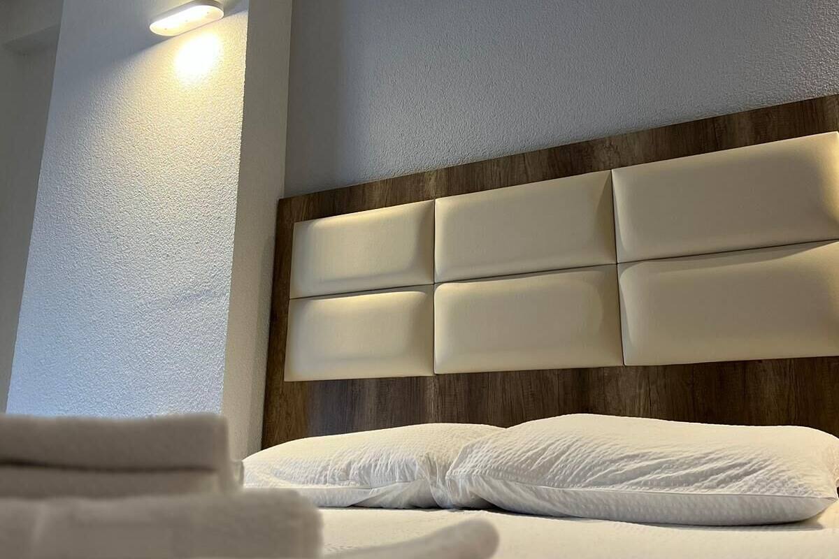 Ein Hotelzimmer mit Bett, Kopfteil und Wandleuchte.
