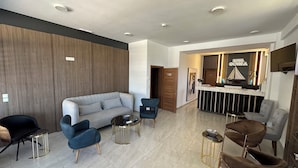 Eine moderne Hotelhalle mit Empfangstresen, Sitzgelegenheiten und einer Holzwand.