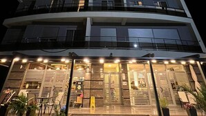 Ein mehrstöckiges Hotel mit geschwungener Fassade, Balkonen auf jeder Etage sowie einem Restaurant und einer Hotellobby im Erdgeschoss.