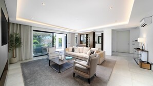 Un salon moderne comprenant un canapé, des fauteuils, une table basse et un téléviseur.