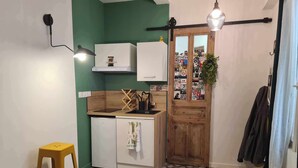 A compact kitchen with a wooden countertop, a white refrigerator, and a wooden door with stickers. - La Sainte Madeleine (Gap)
