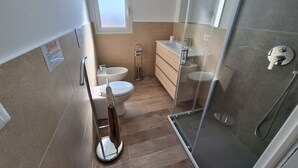 Un baño moderno con inodoro, lavamanos y ducha.