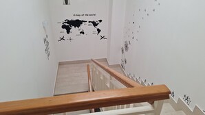 Una escalera con barandilla de madera que lleva a un rellano con un mapa mundial y plantas en macetas.