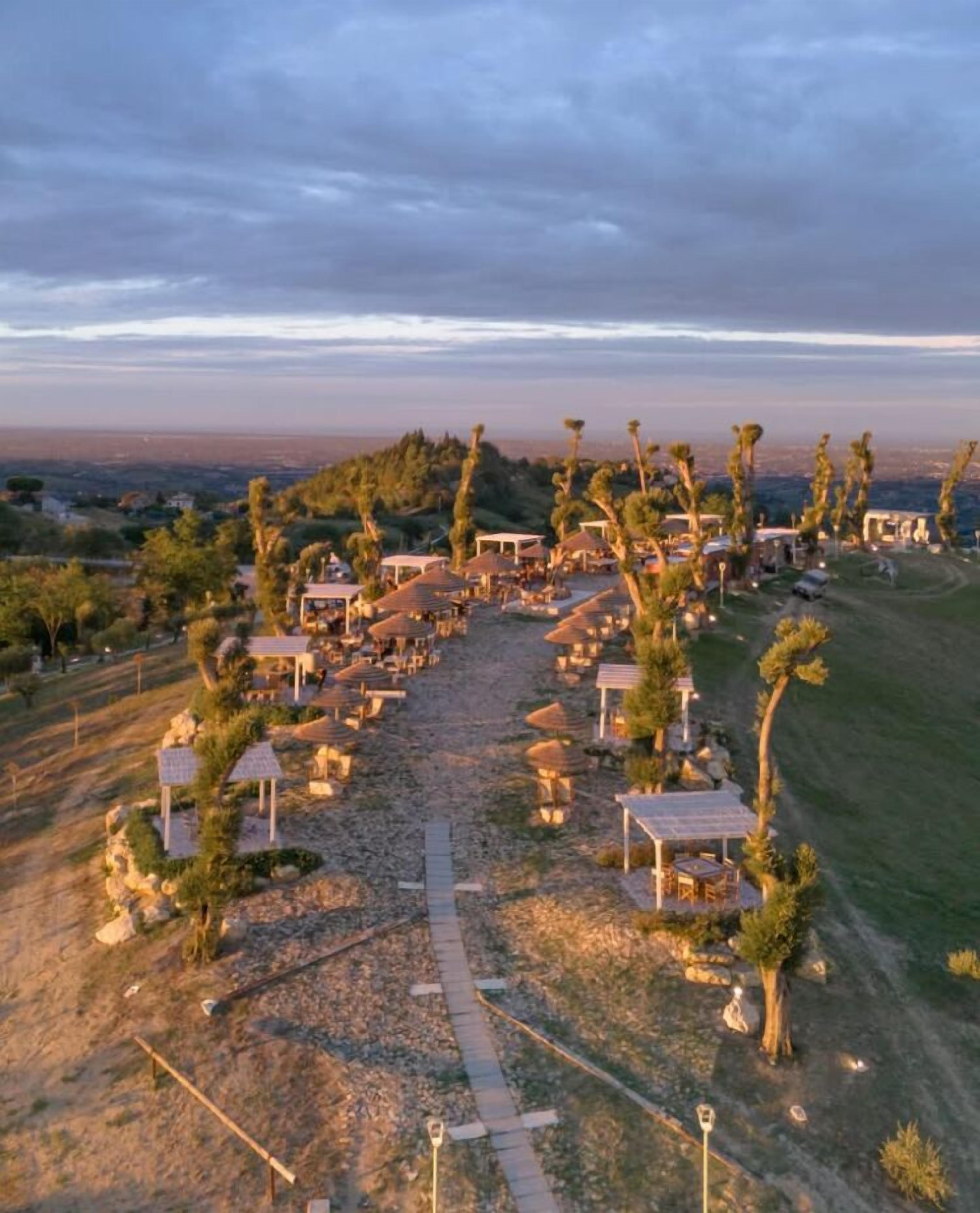 An aerial view of a resort with multiple structures, pathways, and palm trees.