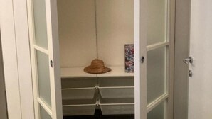 A walk-in closet with open doors, featuring a hat on the shelf and a decorative item on the wall. - Bel Respiro, an enchanting getaway in the heart of Monteleone hillside (Roncofreddo)