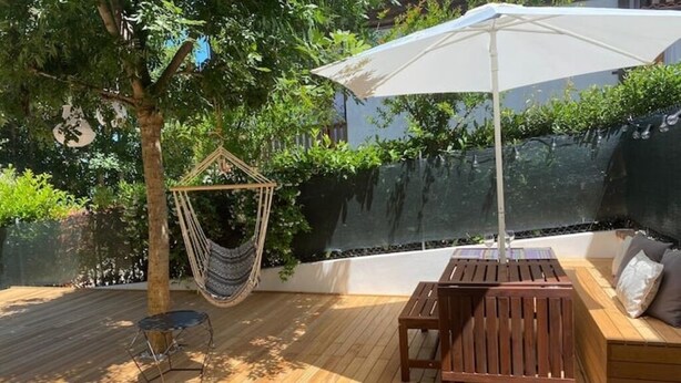 A wooden deck with a hammock, a table, and a bench with cushions. - Bel Respiro, an enchanting getaway in the heart of Monteleone hillside (Roncofreddo)