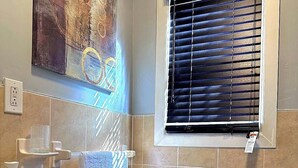 A bathroom with a white sink, toilet, and window with blinds.