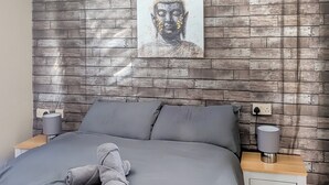 A bedroom with a grey bed, two bedside lamps, a wooden nightstand, and a wall-mounted painting. - 3 bedroom accommodation in Moota, Near Cockermouth (Moota, Near Cockermouth)