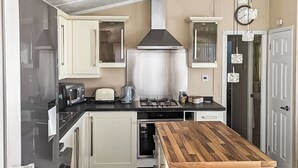 A compact kitchen with white cabinets, a wooden countertop, a gas stove, and a stainless steel range hood. - 3 bedroom accommodation in Moota, Near Cockermouth (Moota, Near Cockermouth)