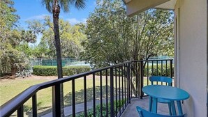 A balcony with a blue table and chairs, surrounded by greenery and trees. - Pickleball/Tennis, Pool, Cozy Villa, Fast WIFI, 5 Minute Walk to the Beach (Hilton Head Island)