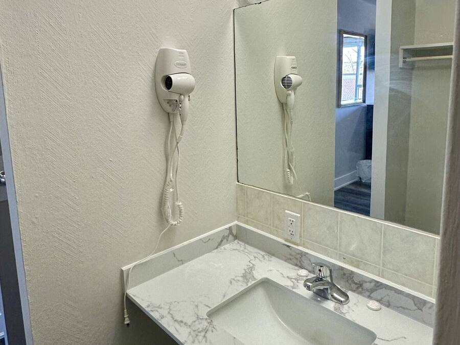 A bathroom with a marble sink, a mirror, and two wall-mounted hair dryers.
