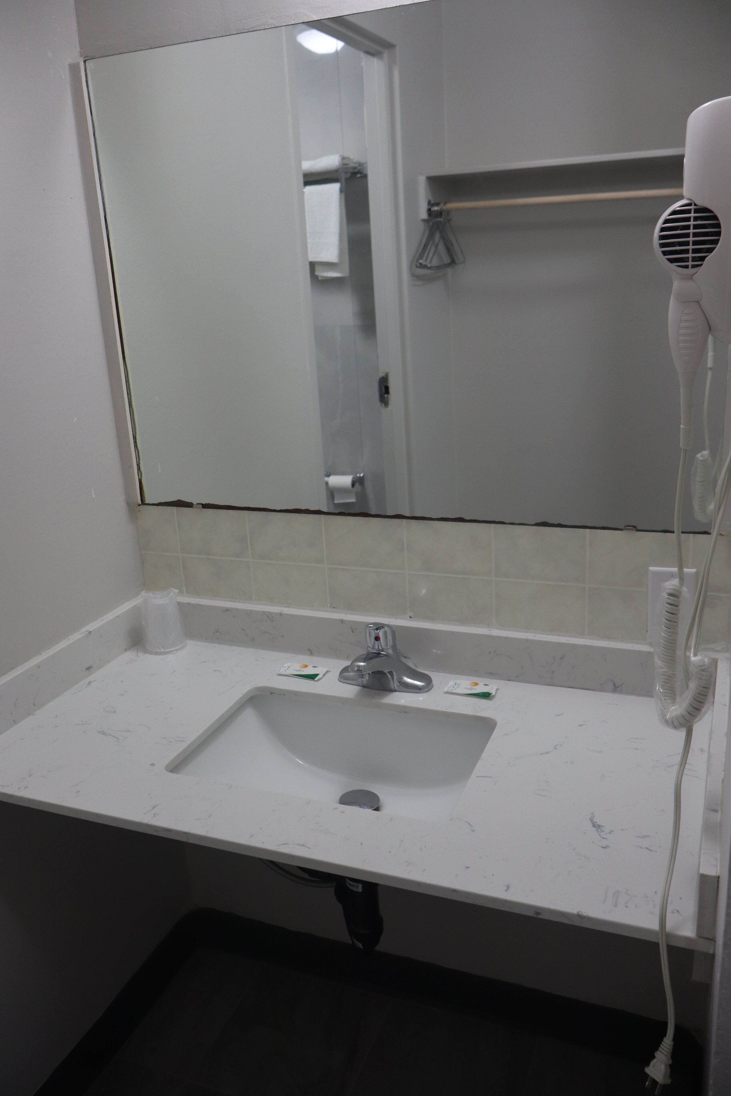A bathroom with a white sink, a mirror, and a hairdryer.