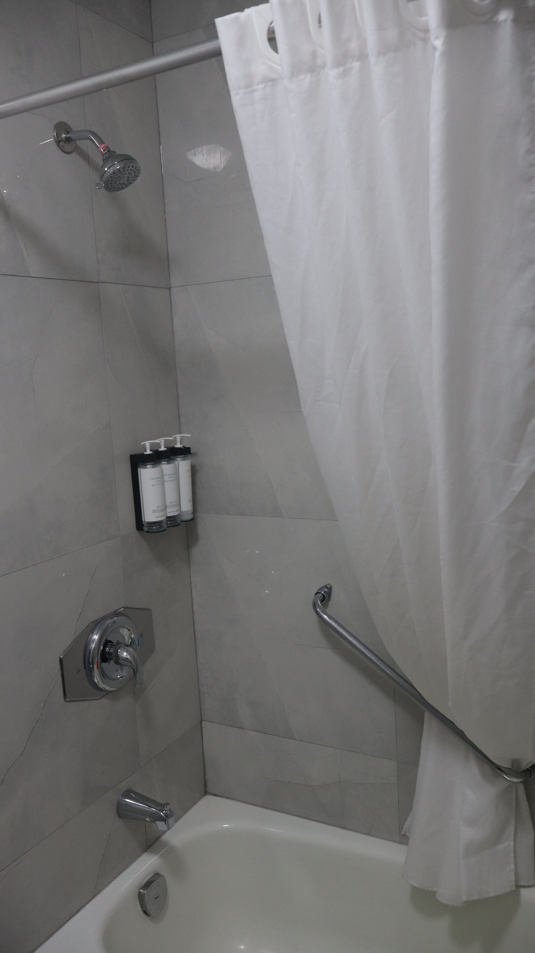 Un baño con ducha, bañera y barra de apoyo.