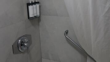 Un baño con ducha, bañera y barra de apoyo.