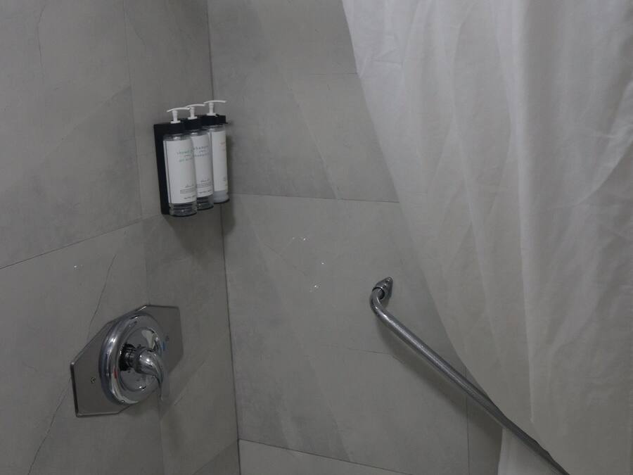 Un baño con ducha, bañera y barra de apoyo.