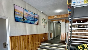 Um hall de hotel com painéis de madeira, uma escadaria e vista para o interior.