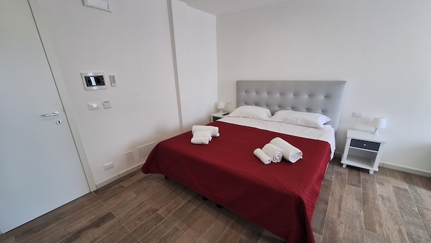 A hotel room with a bed, a nightstand, a wardrobe, and a door. - Room-double Bedroom With Double bed (Terrasini)