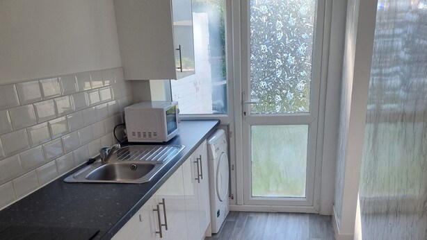 Una cocina moderna con un lavamanos, microondas, horno y ventana con vista a follaje.